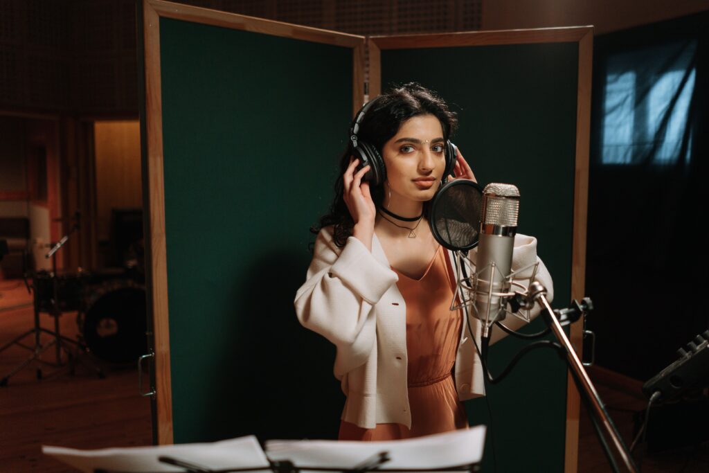 A female musician recording vocals in a professional music studio.